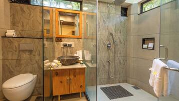 Un baño con inodoro, tocador de madera y zona de ducha con mampara de vidrio.