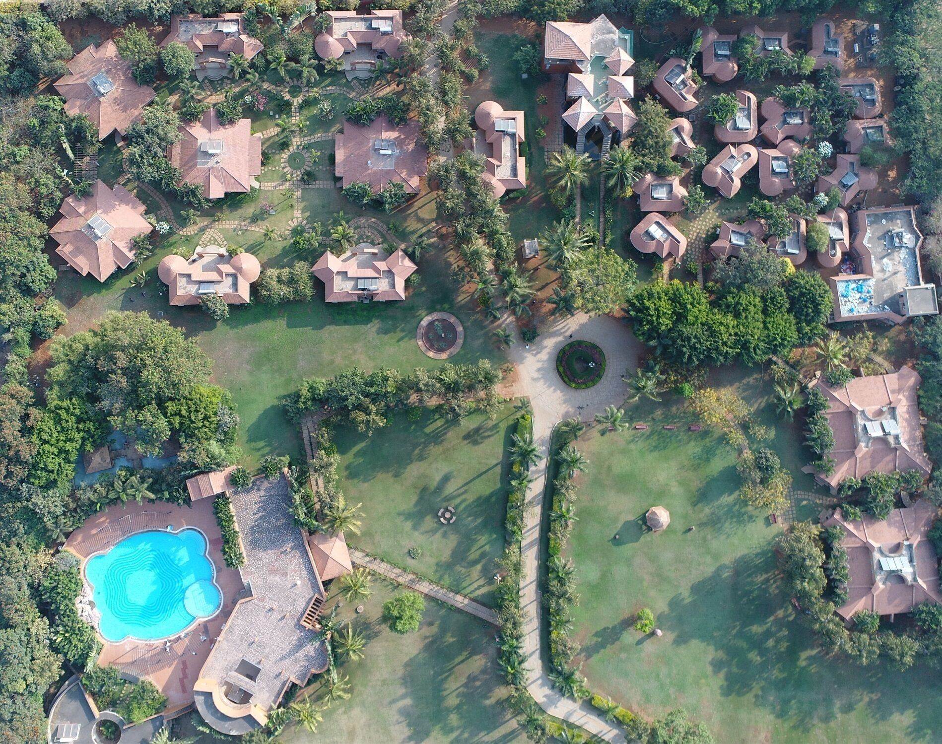 Vista aérea de una zona residencial con varias casas, una piscina y jardines bien cuidados.