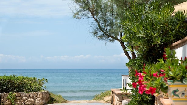 A stone pathway leading to a beach with a view of the sea. - Hotel Villaggio Torre San Vito (Gaeta)