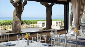A dining table set with white chairs, a vase with yellow flowers, and wine glasses. - Hotel Villaggio Torre San Vito (Gaeta)
