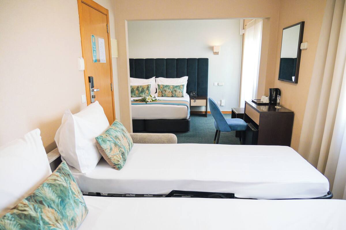 Ein Hotelzimmer mit einem Bett, einem Schreibtisch, einem Stuhl und einem weiteren Bett im Hintergrund.