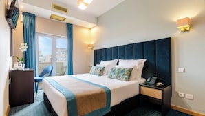 Habitación de hotel con una cama grande, un escritorio, una silla y vistas a la ciudad.