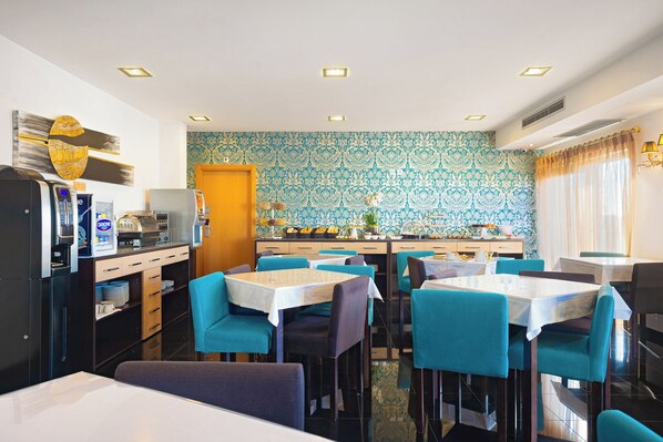 Un espace repas avec des tables et des chaises, une machine à café et un mur décoré de motifs.