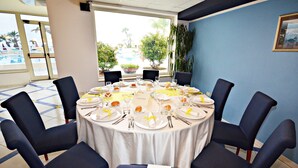 A round dining table set for six with chairs, a white tablecloth, and yellow sashes. - Grand Hotel La Playa (Sperlonga)