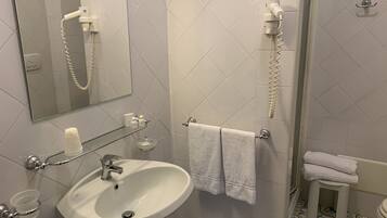 Ein Badezimmer mit Waschbecken, Spiegel, Handtuchhalter und Duschbereich.