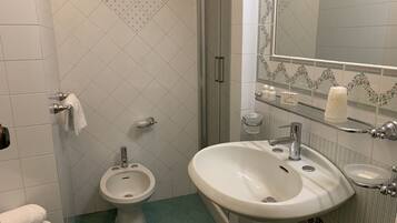 Un bagno con bidet, lavandino, specchio e WC.