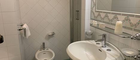Un baño con bidé, lavamanos, espejo y retrete.