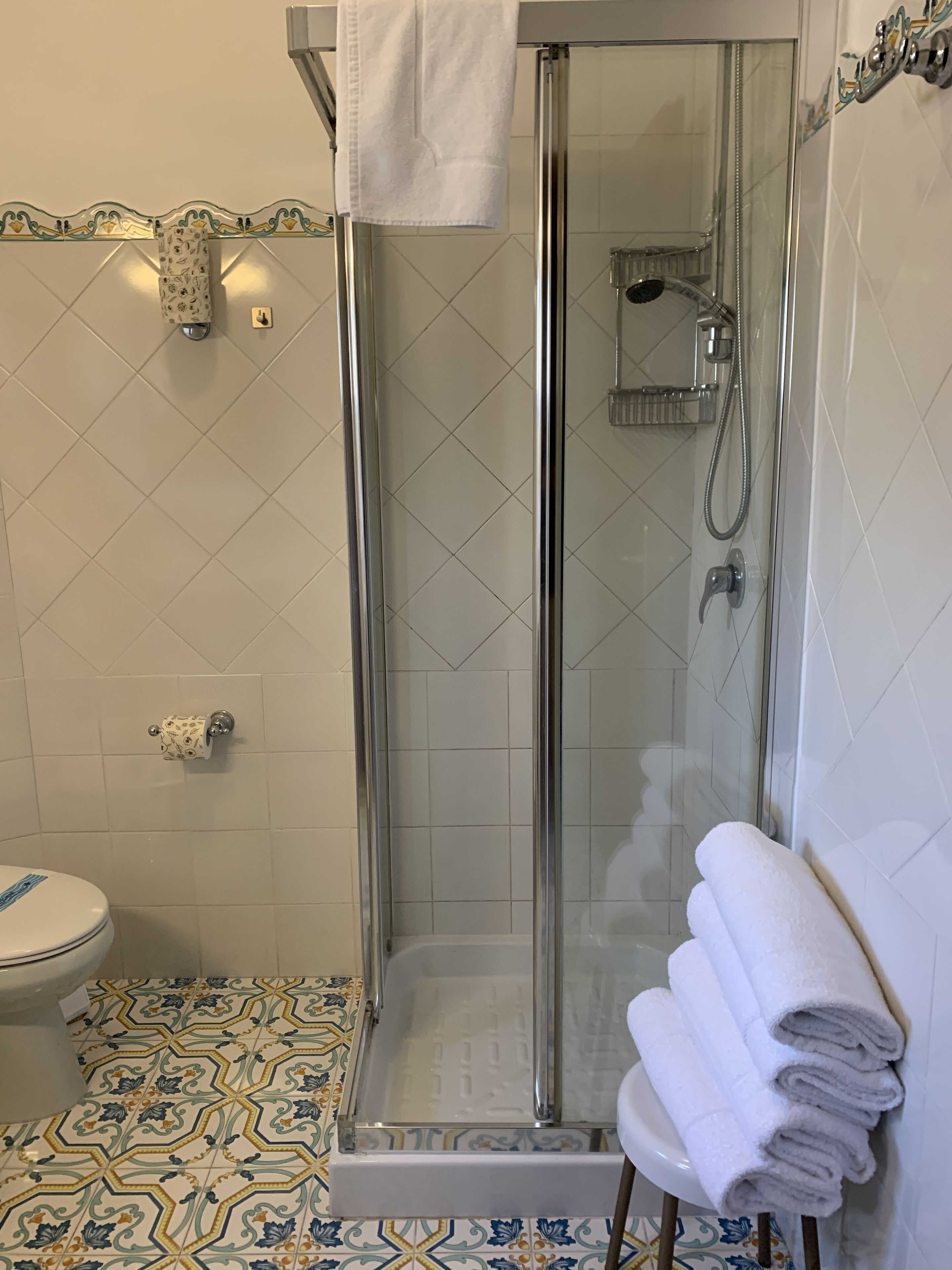 A bathroom with a glass-enclosed shower, a toilet, and a sink.