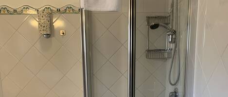 A bathroom with a glass-enclosed shower, a toilet, and a sink.