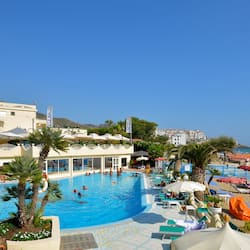 Relax by the pool surrounded by sun loungers and umbrellas, with a view of the beach and ocean.