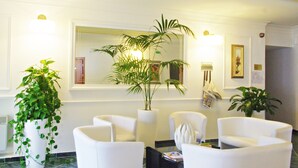 A lobby with white armchairs, a large mirror, and potted plants. - Grand Hotel La Playa (Sperlonga)