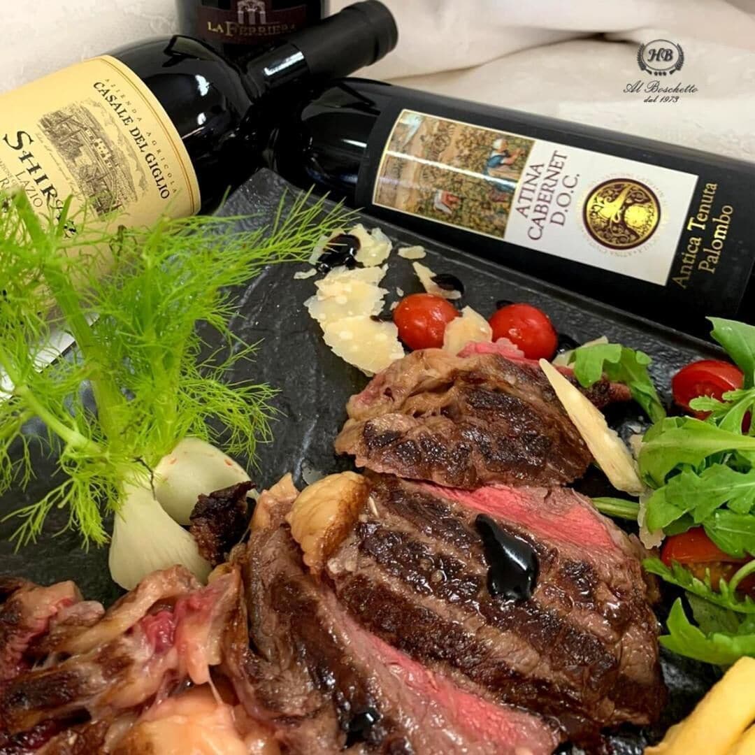 Ein Steak mit Gemüse und einer Weinflasche auf einer Schiefertafel.