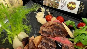Ein Steak mit Gemüse und einer Weinflasche auf einer Schiefertafel.