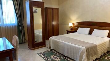 A hotel room with a bed, a nightstand, a mirror, a desk, and a chair.