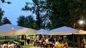 Evento al aire libre con mesas y sillas bajo toldos blancos, rodeado de árboles.
