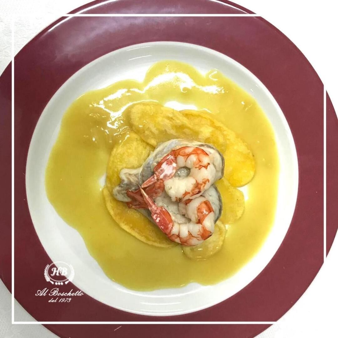 A plate with a seafood dish, possibly shrimp, served with a yellow sauce and bread.