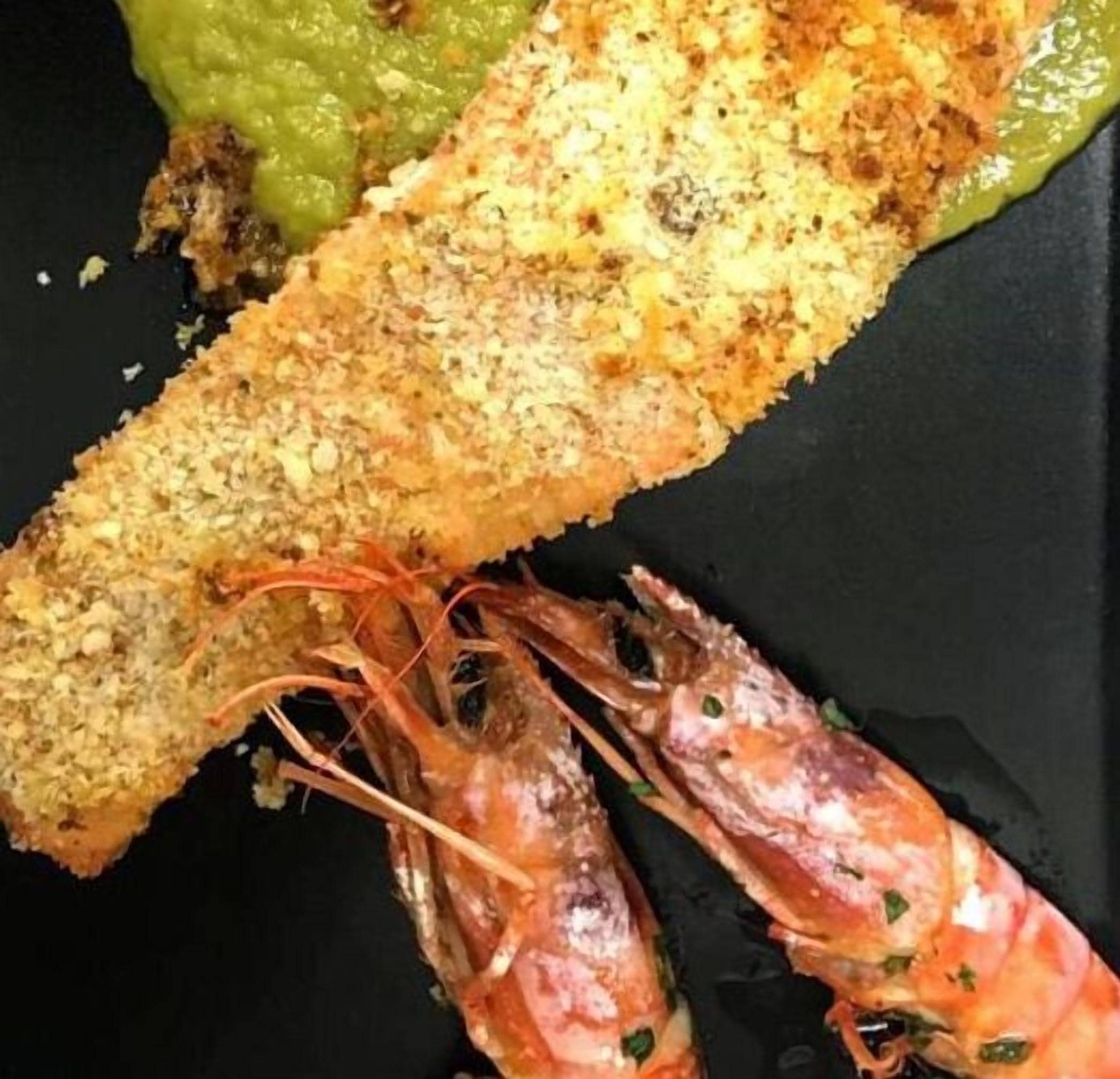 A seafood dish with breaded shrimp and a green sauce.