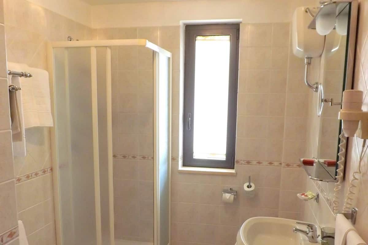 A bathroom with a shower, toilet, sink, and a window.