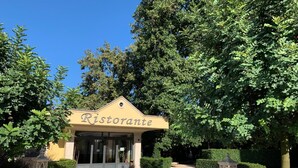 Entrada a un restaurante con un letrero que dice "Ristorante" y un logotipo circular en el suelo.