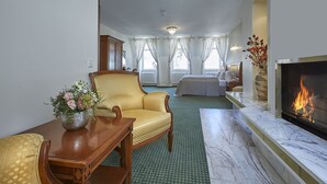 A hotel room with a bed, a seating area with a chair and table, a fireplace, and a window with curtains. - Hotel Beek (Baden-Baden)