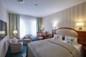 A hotel room with a large bed, a desk, a chair, and a television. - Hotel Beek (Baden-Baden)