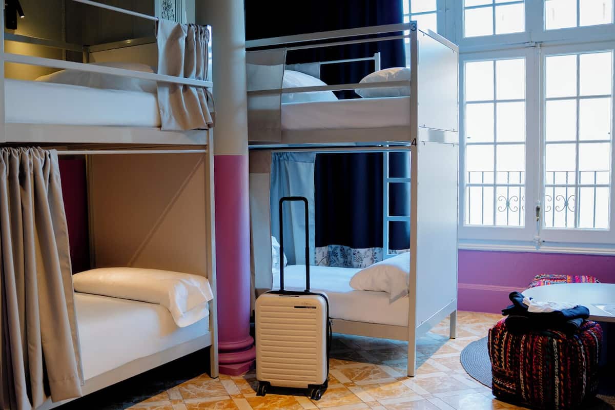 Une chambre avec un lit superposé, une valise et une table ronde.