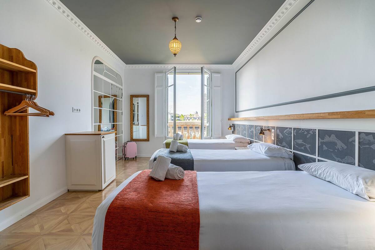 Une chambre d’hôtel avec deux lits, une armoire, un miroir et une vue sur la ville.