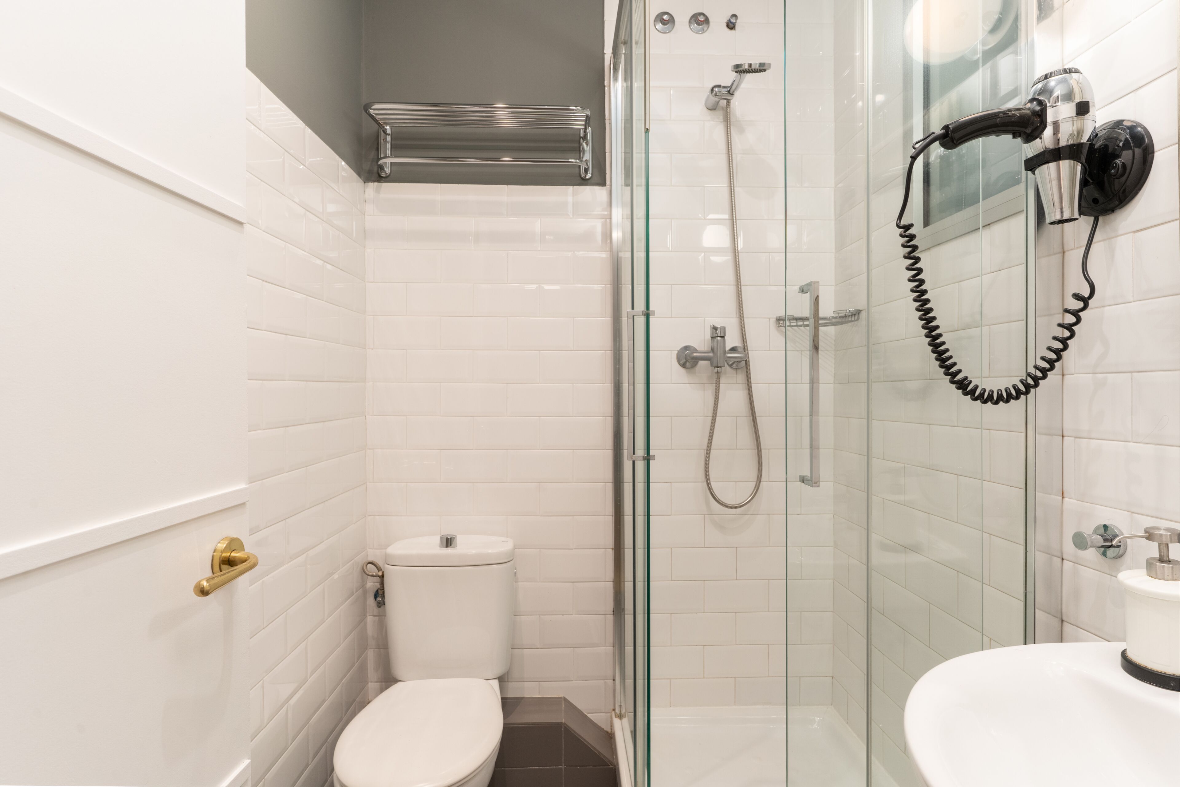 A bathroom with a toilet, a glass-enclosed shower, and a sink.