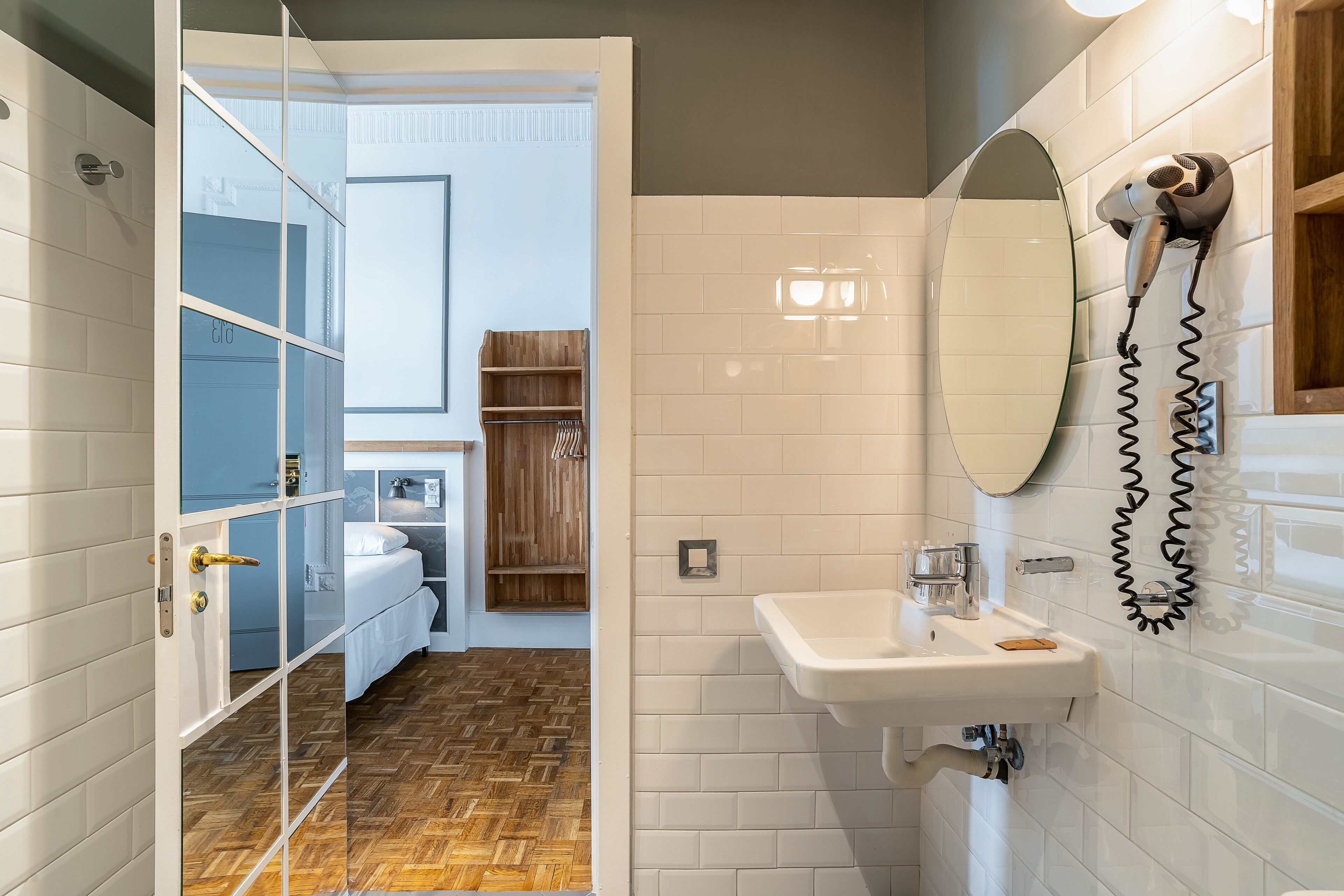 A modern bathroom with a glass shower enclosure, a white sink, and a hairdryer mounted on the wall.