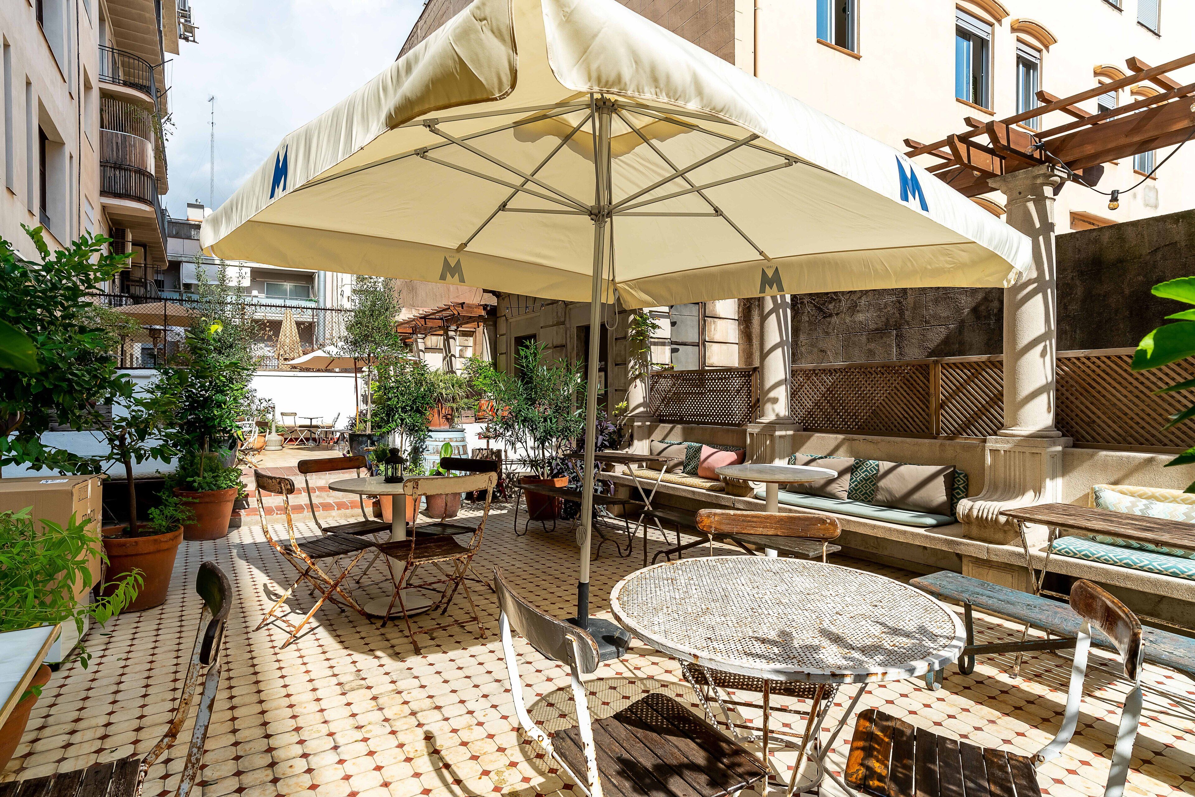 An outdoor patio with a round table, chairs, a sofa, and an umbrella.