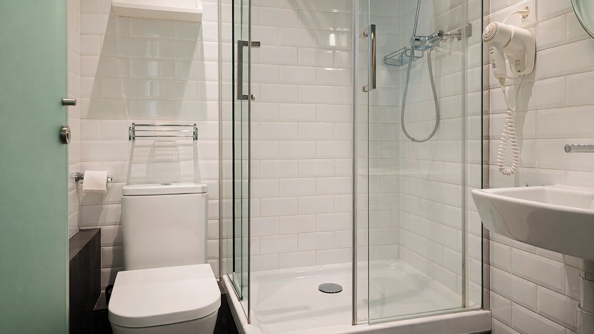 A modern bathroom with a glass-enclosed shower, a toilet, and a sink.