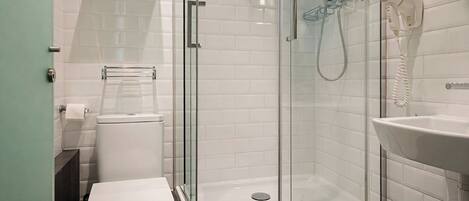 A modern bathroom with a glass-enclosed shower, a toilet, and a sink.