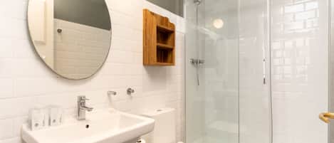 A bathroom with a sink, toilet, and glass shower enclosure.