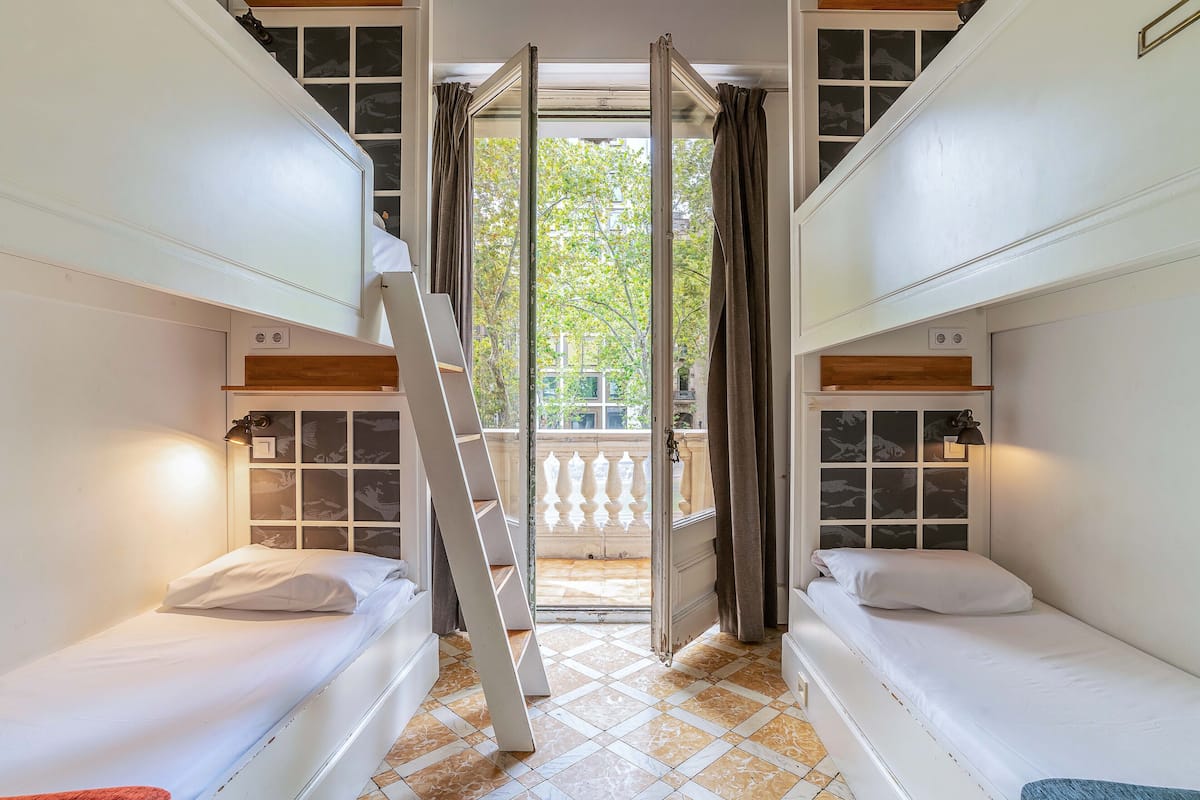 Une chambre de dortoir avec des lits superposés, une échelle et un balcon avec des rideaux.