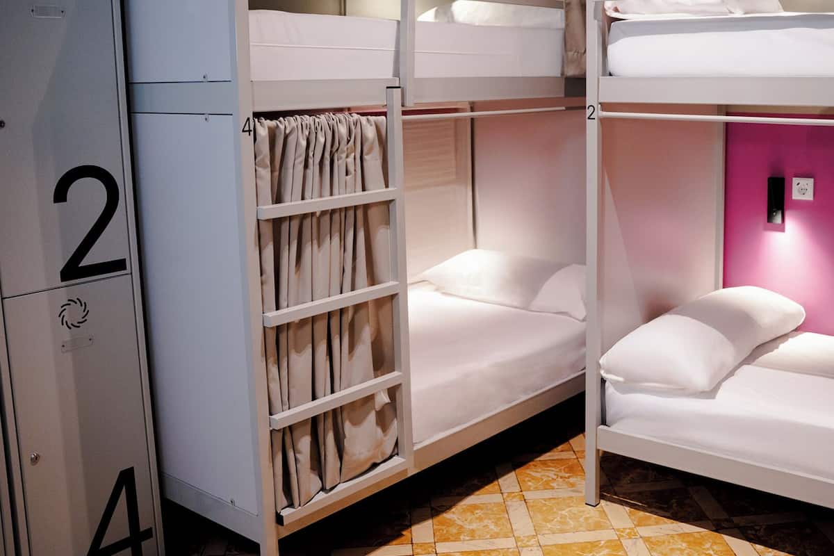 Une chambre avec un lit superposé, deux lits, une armoire et le chiffre « 2 » peint sur le mur.