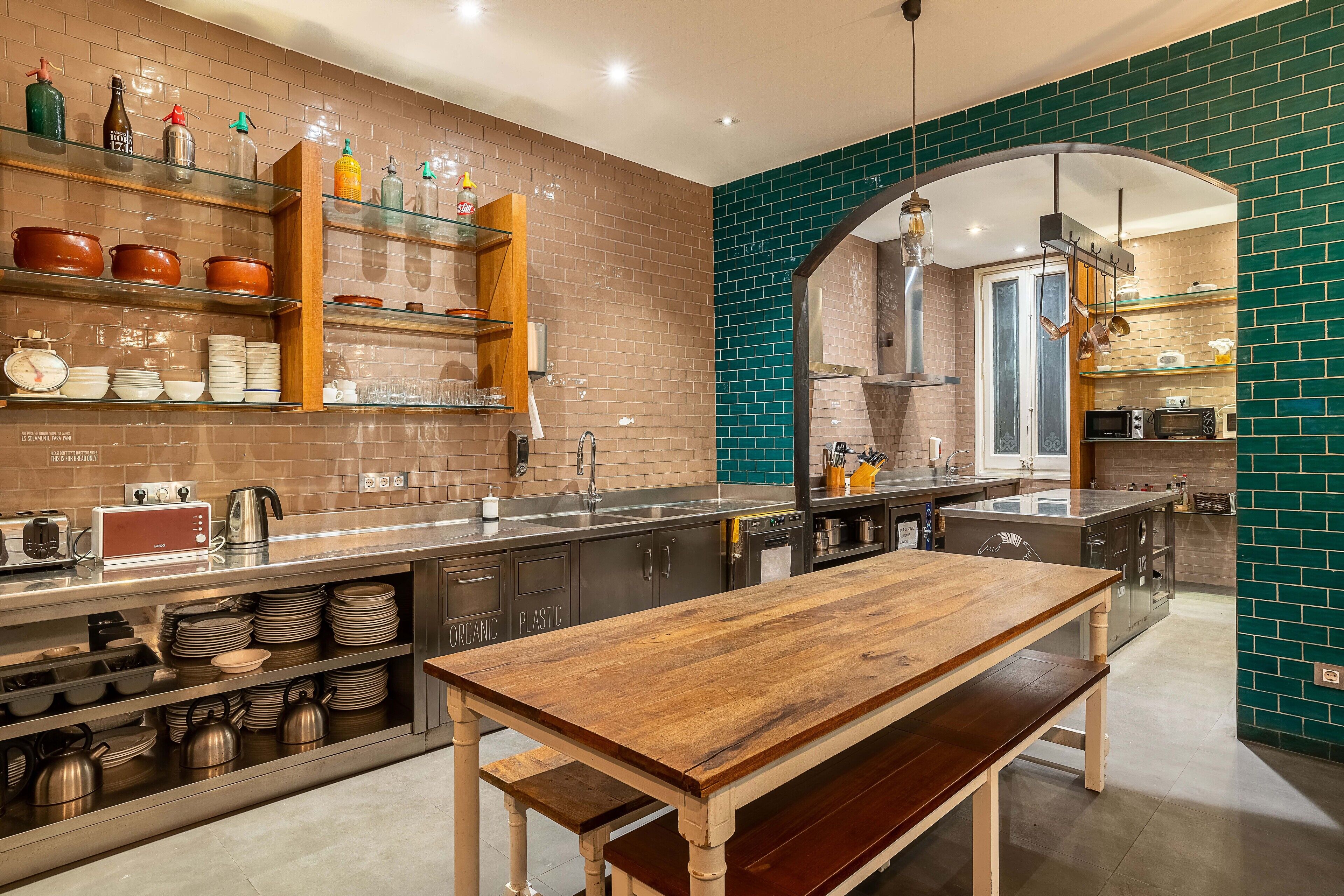 A modern kitchen with a wooden table, stainless steel appliances, and a brick backsplash.