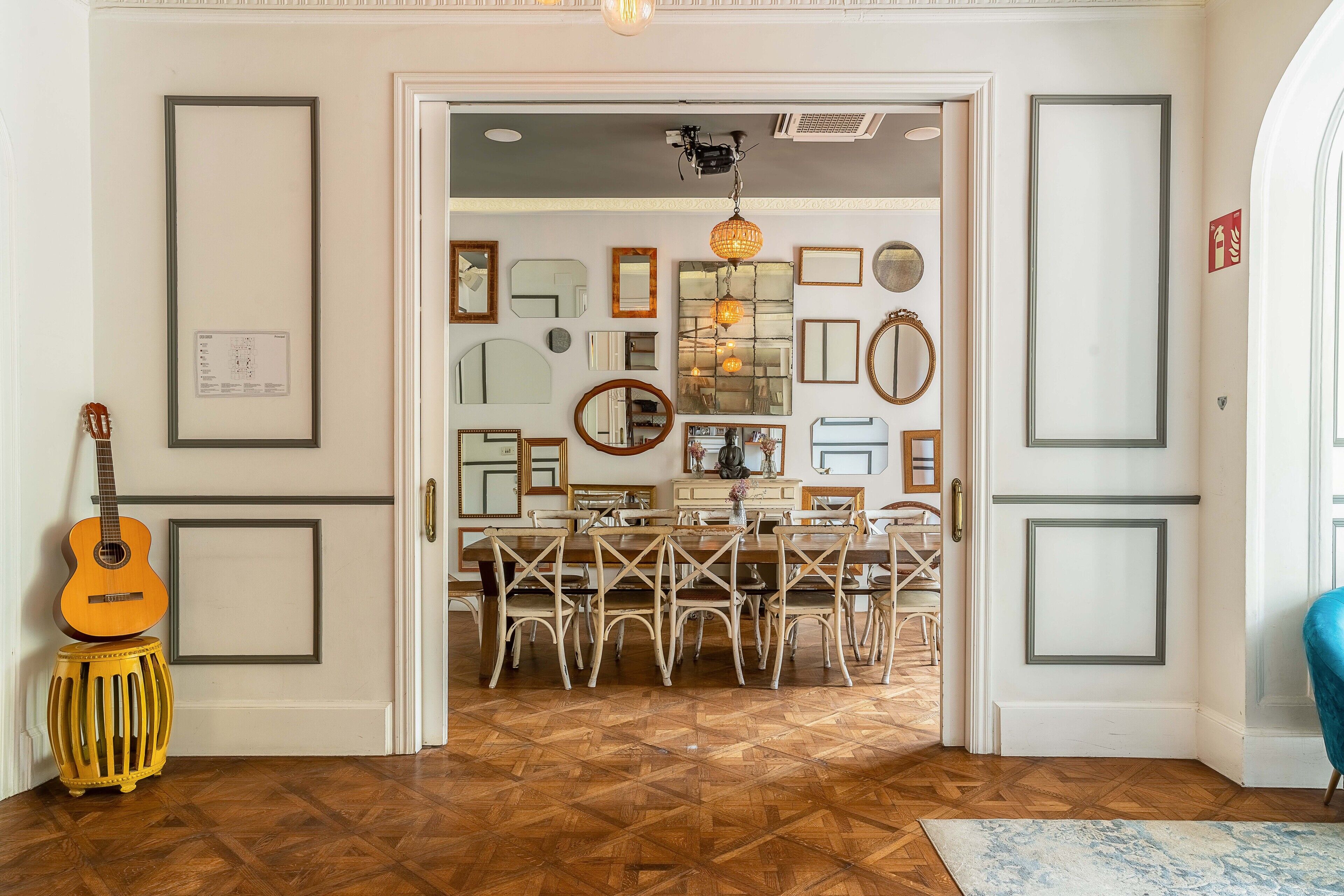Un espace repas doté d’un parquet en bois disposé en motif à chevrons, d’une table à manger avec des chaises et d’un luminaire suspendu.