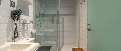 A modern bathroom with a glass-enclosed shower, a white sink, and a toilet.