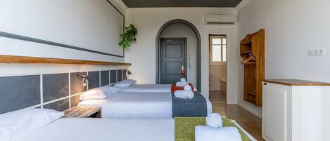 Habitación de hotel con tres camas, un escritorio y un armario.