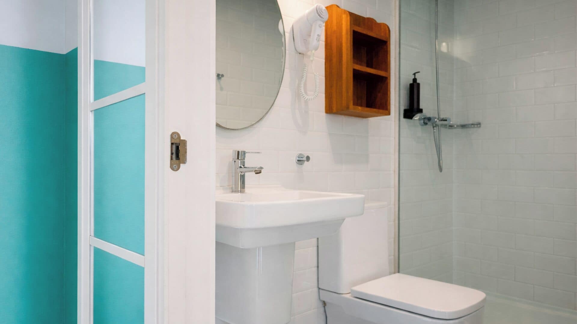 Une salle de bain avec un lavabo blanc, des toilettes, une douche en verre et un meuble à pharmacie en bois.