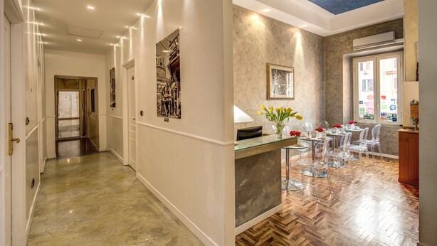 A hotel lobby with a marble floor, a reception desk, clear chairs, and a dining area with a wooden floor. - Relais Conte di Cavour de Luxe (Rome)