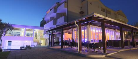 A modern building with a covered outdoor seating area and a glass facade.