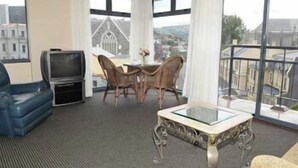Una sala de estar moderna con televisor, una mesa de comedor con sillas y un balcón con vistas a la ciudad.