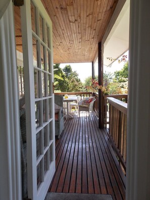 Una terraza de madera con barandilla, un banco y una mesa.