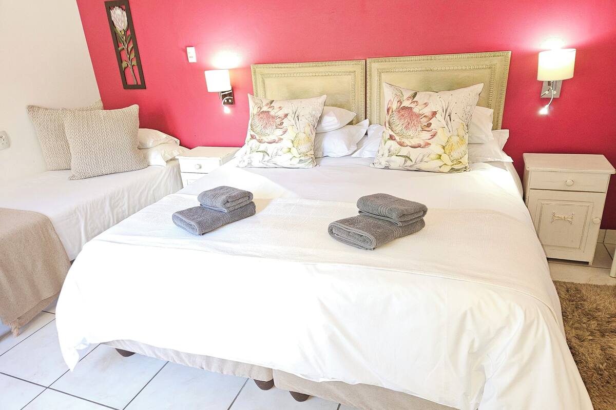 Una habitación de hotel con una cama grande, dos mesitas de noche y una lámpara fijada a la pared.