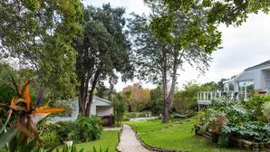 A garden with a gravel path leading to a house with a white exterior and a deck.