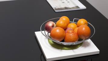 Eine Glaskugel mit Orangen und einem Apfel auf einer weißen Tischdecke auf einem schwarzen Tisch.