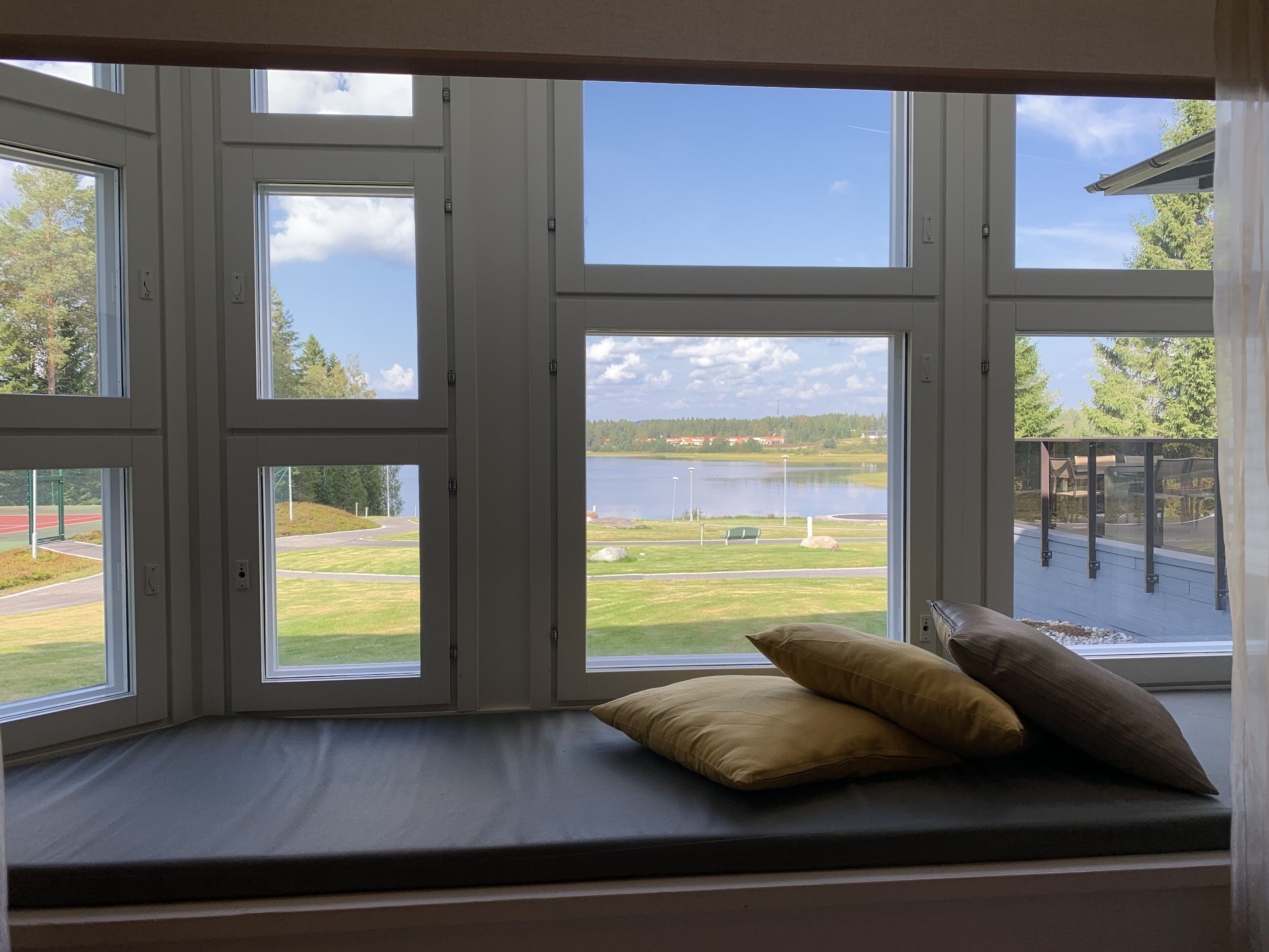 Una habitación con un amplio ventanal que da a un lago y un campo deportivo.