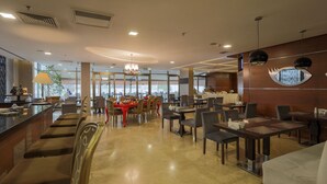 Ein modernes Restaurant mit Barbereich, Esstischen und Stühlen.