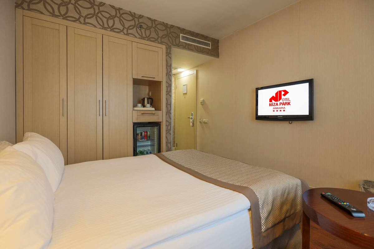 Habitación de hotel con una cama grande, televisión montada en la pared y un minibar.